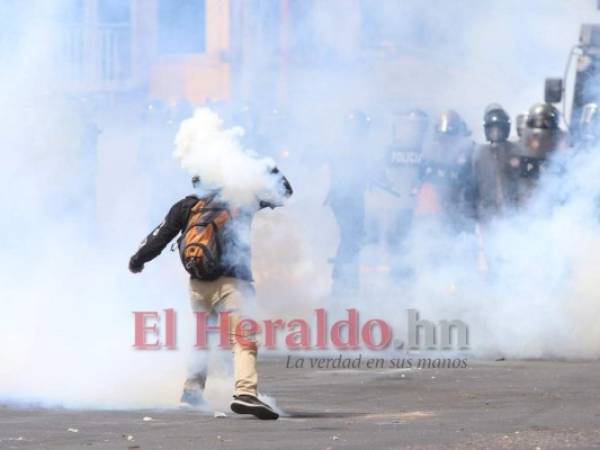 Un joven lanza a un grupo de policías una bomba lacrimógena que recogió del suelo en el bulevar Morazán durante una manifestación alterna que realizó el Partido Libertad y Refundación (Libre) este 15 de septiembre, Día de la Independencia de Honduras. Foto: Alex Pérez/ EL HERALDO.