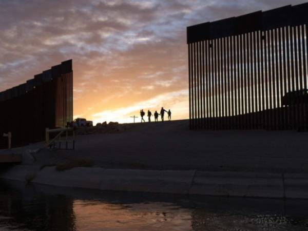 Un par de familias migrantes de Brasil atraviesan un hueco en el muro fronterizo para llegar a Estados Unidos después de cruzar desde México en Yuma, Arizona. (AP Foto/Eugene Garcia).