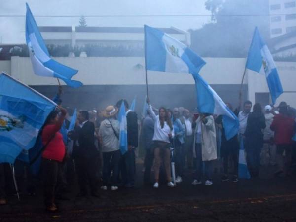 Visto a través de una nube de humo de fuegos artificiales, la gente celebra como la Comisión Internacional de las Naciones Unidas contra la Impunidad en Guatemala, conocida por sus siglas en español CICIG.