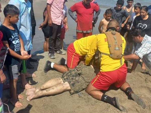 Momento en que los rescatistas intentaban salvar la vida de este hondureño en la playa de Tela.