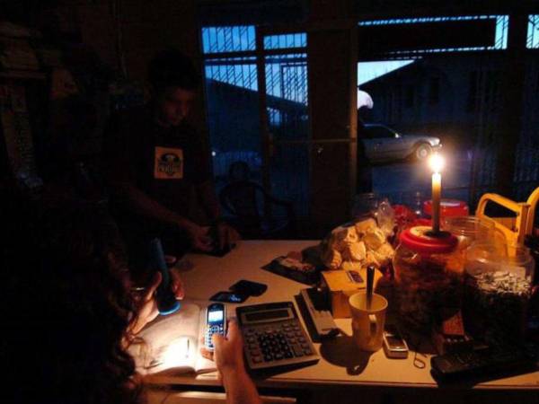 Con linternas y teléfonos celulares se alumbran los pobladores del valle de Sula ante los constantes apagones.