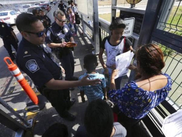 Un agente fronterizo estadounidense verificando los documentos de migrantes antes de ser llevados a solicitar asilo en Estados Unidos. Foto AP