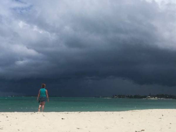 Una mujer camina en la playa cuando se acerca una tormenta en Nassau, Bahamas. Foto: Agencia AFP.