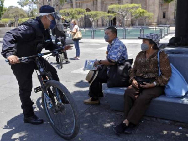 Un oficial de la Policía Municipal pide a las personas en una plaza que abandonen el lugar ya que no se permite estar en espacios públicos en el estado de Jalisco como medida preventiva contra la propagación del nuevo coronavirus, Covid-19, en Guadalajara, México. AFP.