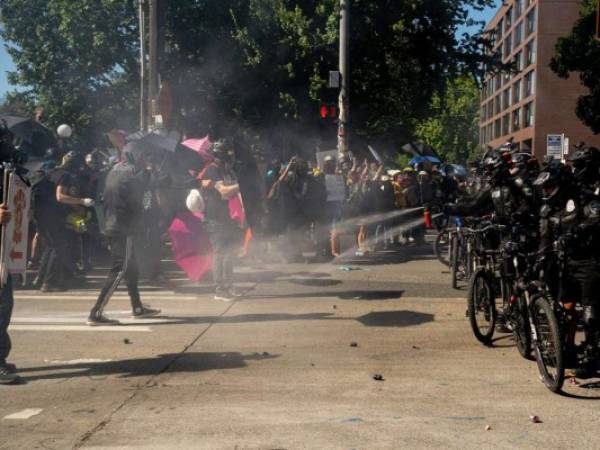 La policía antidisturbios se enfrentó a los manifestantes, algunos de los cuales levantaron paraguas para evitar ser alcanzados por el gas pimienta. Foto: AFP