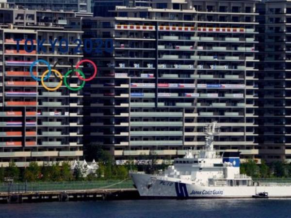 Banderas nacionales colgadas de los balcones en los alojamientos para deportistas, mientras Tokio se prepara para los Juegos Olímpicos, el domingo 18 de julio de 2021. Los JJOO, aplazados por la pandemia, comienzan el 23 de julio sin espectadores en la mayoría de las sedes. (AP Foto/Charlie Riedel)