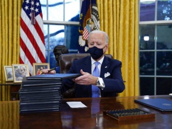 El presidente Joe Biden firma sus primeras órdenes ejecutivas el miércoles 20 de enero en la Oficina Oval de la Casa Blanca, en Washington. Foto: AP.