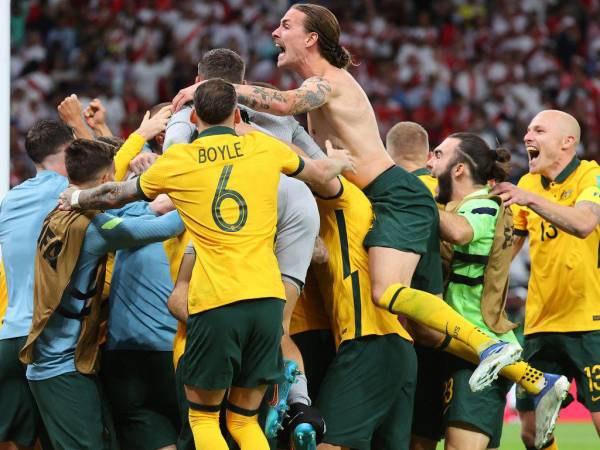 Los jugadores de Australia celebran ganar el partido de play-offs entre confederaciones de la Copa Mundial de la FIFA 2022 entre Australia y Perú el 13 de junio de 2022, en el estadio Ahmed bin Ali en la ciudad qatarí de Ar-Rayyan. Australia venció a Perú en una tanda de penales a muerte súbita para asegurar el penúltimo lugar libre en la final de la Copa del Mundo.