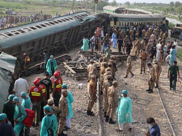 Guardabosques paramilitares y voluntarios inspeccionan los vagones en el lugar del accidente luego del descarrilamiento de un tren de pasajeros en Nawabshah el 6 de agosto de 2023.