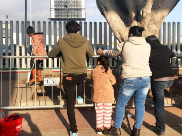 Varias personas que buscan solicitar asilo en Estados Unidos esperan en un puente fronterizo de Tijuana, México. Foto: AP.