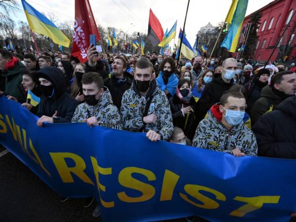 Los manifestantes gritan consignas mientras marchan detrás de una pancarta que dice “Los ucranianos resistirán” con los colores de la bandera nacional durante una manifestación en Kiev el 12 de febrero de 2022, realizada para mostrar unidad en medio de las advertencias de Estados Unidos sobre una inminente invasión rusa.