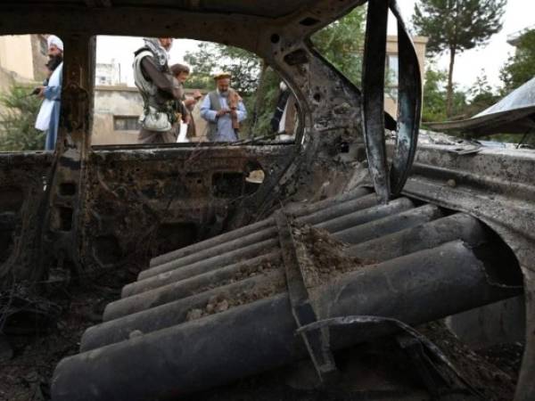 Combatientes talibanes investigan un automóvil dañado después de que se dispararan múltiples cohetes en Kabul el lunes 30 de agosto. FOTO: AFP