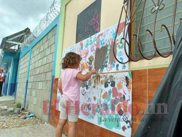 Niña migrante de origen cubano pinta en un mural, en un evento de asistencia psicosocial de la Cruz Roja.