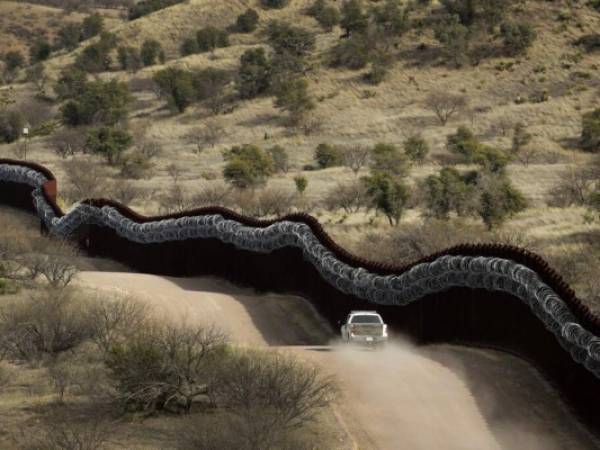 Fotografía de archivo del 2 de marzo de 2019 de agentes de la Oficina de Aduanas y Protección Fronteriza de Estados Unidos patrullando junto a una barrera cubierta de alambre de púas a lo largo de México, al oriente de Nogales, Arizona. Foto: AP