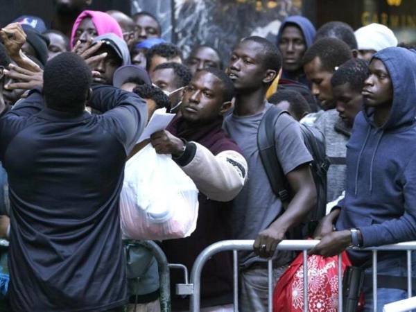 Centenas de migrantes esperan en fila frente a un centro de acogida ubicado en el Hotel Roosevelt en Manhattan en busca de un alojamiento gratuito