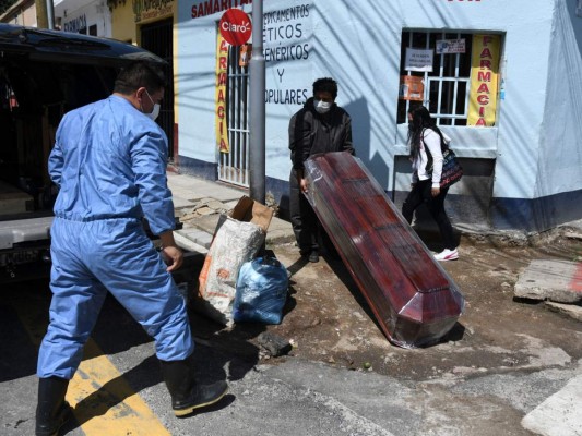 Empleados de una empresa funeraria cargan el ataúd de una víctima de COVID-19, desde la morgue para llevarlo al cementerio de La Verbena en la Ciudad de Guatemala. Foto: Agencia AFP.