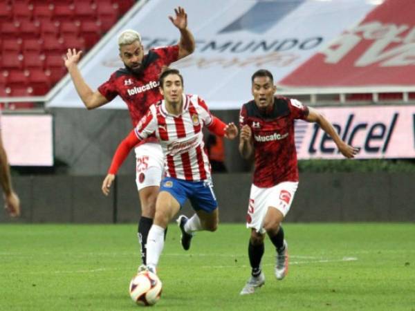 Isaac Brizuela de Guadalajara compite por el balón con Pedro Canelo y José Vázquez de Toluca, durante su partido de fútbol del Torneo de Clausura Mexicana, en el estadio Akron, en Guadalajara, Estado de Jalisco, México, el 16 de enero , 2021, durante la pandemia del coronavirus Covid-19.Ulises Ruiz / AFP.