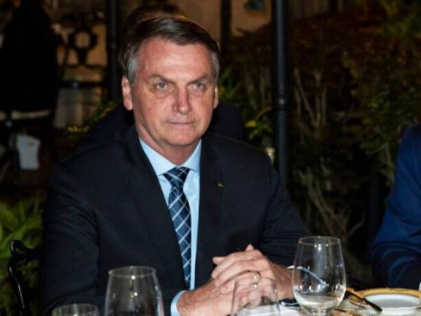 Brazil's President Jair Bolsonaro puts on a mask during a press conference on the new coronavirus at the Planalto Presidential Palace in Brasilia, Brazil, Wednesday, March 18, 2019. For most people COVID-19 causes mild or moderate symptoms. For others, especially the elderly and people with existing health problems, it can cause many other serious illnesses, including pneumonia. (AP Photo/Andre Borges)