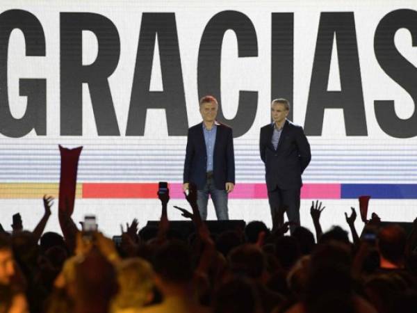 El presidente argentino Mauricio Macri (L), candidato presidencial del partido 'Juntos por el Cambio', y su socio Miguel Angel Pichetto gesticulan a sus votantes después de ser derrotados por el presidente electo Alberto Fernández del 'Frente de Todos'. Foto AFP