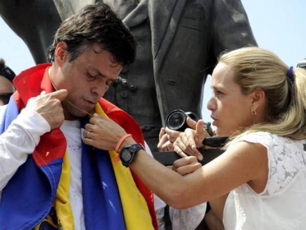 Leopoldo López, un ardiente opositor del gobierno socialista de Venezuela que enfrenta una orden de arresto después de que el presidente Nicolás Maduro ordenó su arresto por homicidio e incitación a la violencia, recibe un collar de Cristo de su esposa Lilian Tintori, durante una manifestación antes de entregarse. Autoridades, en Caracas.