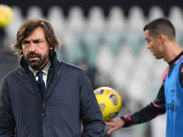 El entrenador italiano de la Juventus, Andrea Pirlo, camina sobre la cancha mientras el delantero portugués de la Juventus, Cristiano Ronaldo (R), calienta antes del partido de fútbol de la Serie A.