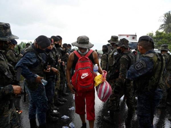 Un migrante hondureño, parte de una caravana que se dirige a los Estados Unidos, camina bajo la lluvia junto a miembros del Ejército de Guatemala, en Entre Ríos, Guatemala, luego de cruzar la frontera desde Honduras. Foto: Agencia AFP.