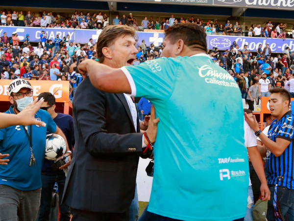 Un partidario de Querétaro (R) se enfrenta al entrenador en jefe argentino de Querétaro, Hernán Cristante (L) durante el partido de fútbol del torneo Clausura mexicano entre Querétaro y Atlas en el estadio Corregidora.