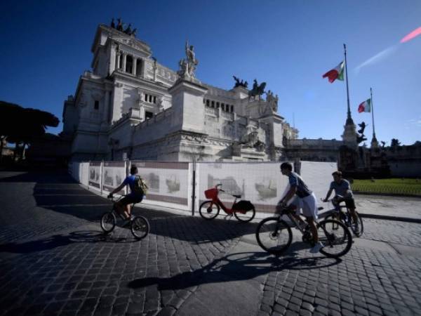 El ciclista pasa por el sitio de trabajo del metro con el monumento de Altare della Patria en el centro de Roma, ya que el bloqueo introducido hace dos meses para combatir la propagación de la pandemia de Covid-19 causada por el nuevo coronavirus comienza a disminuir. Foto: Agencia AFP.