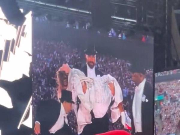 Travis Kelce cargando a Taylor Swift durante su concierto.