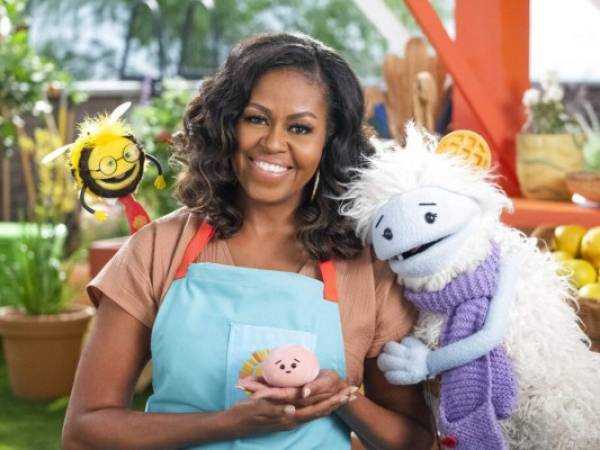 En esta imagen difundida por Netflix, la ex primera dama estadounidense Michelle Obama con Busy, un títere de abeja, a la izquierda, Mochi, un títere rosado, y Waffles, un títere peludo con orejas de waffle, en el set de la serie de cocina para niños 'Waffles + Mochi'. Obama estrenará el nuevo programa en Netflix el 16 de marzo. Foto: AP