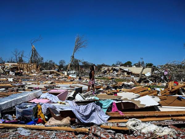 Una mujer camina entre los restos de una casa en Rolling Fork, Mississippi, luego de que un tornado azotara el área, el 26 de marzo de 2023.