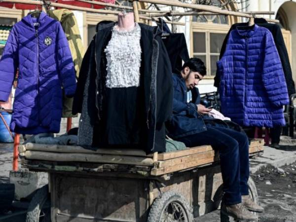 Un vendedor afgano que vende ropa de invierno se sienta en un carrito en un área de mercado en Kabul el 29 de diciembre de 2021. Foto: AFP