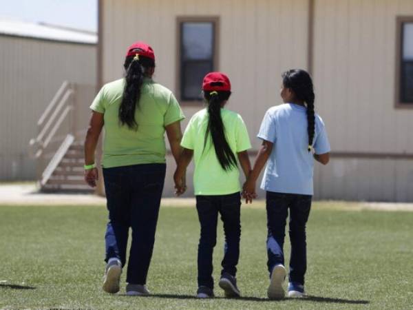 Tres inmigrantes que desean recibir asilo en Estados Unidos caminan tomadas de la mano al salir de una cafetería en el Centro Residencial para Familias del Sur de Texas. Foto: AP.