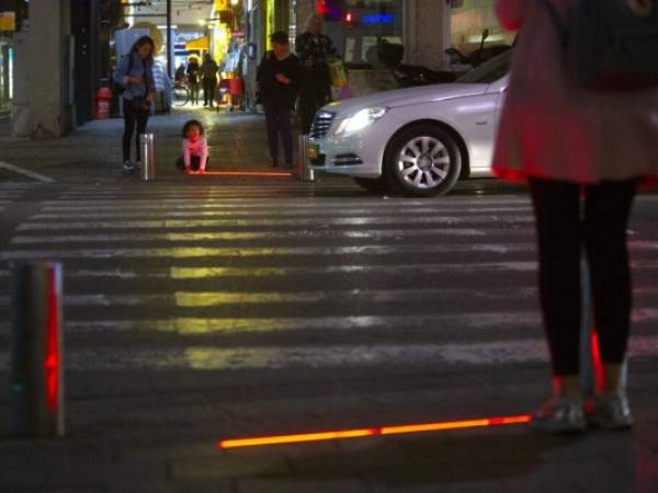 Un niño israelí juega con una luz led en un cruce en Tel Aviv, Israel. Tel Aviv ha empotrado las ledes para proteger a los peatones distraídos por sus teléfonos celulares. (Foto: AP)