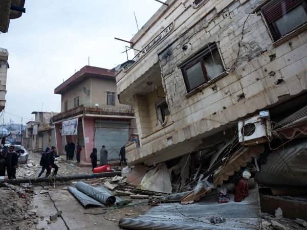 Los residentes caminan a lo largo de un edificio derrumbado luego de un terremoto en la ciudad de Jandaris, en el campo de la ciudad de Afrin, en el noroeste de Siria, en la parte de la provincia de Alepo controlada por los rebeldes, el 6 de febrero de 2023.