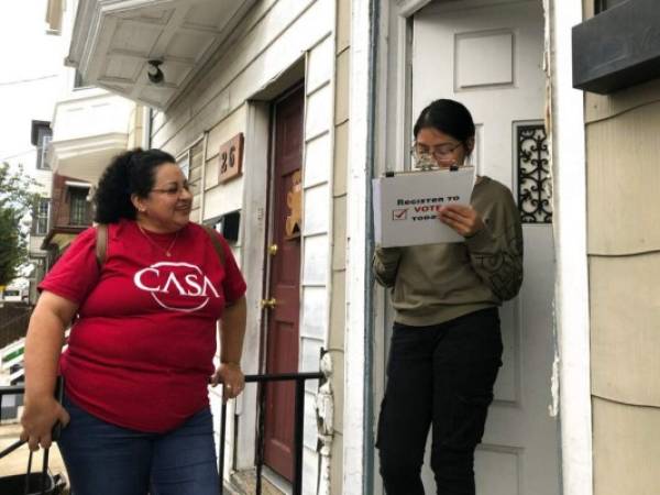 Mirna Orellana, a la izquierda, organizadora comunitaria para el grupo sin fines de lucro We Are Casa, ayuda a Karyme Navarro, a la derecha, a rellenar un formulario para registrarse como votante en York, Pensilvania. Foto: AP.