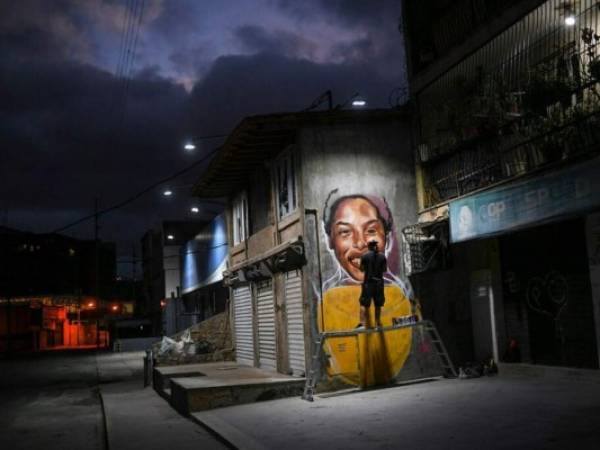 En esta foto del 2 de enero de 2021, el artista callejero Wolfgang Salazar trabaja en una mural de la atleta venezolana Yulimar Rojas en el barrio de Boleita, en Caracas. Foto: AP