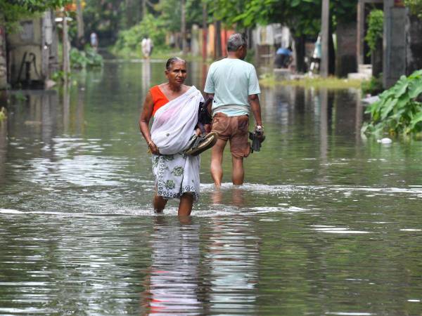 La gente vadea a lo largo de una calle inundada después de las lluvias monzónicas en Patsala, a unos 103 km de Guwahati, en el estado indio de Assam, el 23 de junio de 2023.