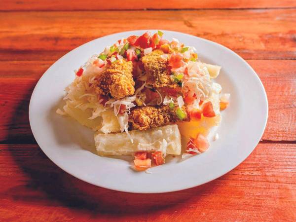 La yuca con chicharrón a menudo se acompaña con ensalada de repollo, encurtido y salsa criolla, dando una dimensión adicional de sabor a esta deliciosa propuesta culinaria.