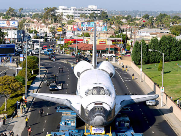 Spectators take in the view of the shuttle Endeavour as it stops in front of the Forum in in Los Angeles on October 13, 2012. the 170,000-pound (77,272 kg) shuttle will travel at no more than 2 mph (3.2 km per hour) along a 12-mile (19km) route from LAX to it's final home at the California Science Center. NASA Space Shuttle Program ended in 2011 after 30 years and 135 missions. AFP PHOTO/Wally Skalij/POOL