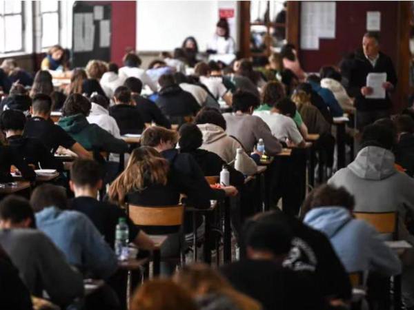 Estudiantes realizan un examen mientras su profesor los supervisa.