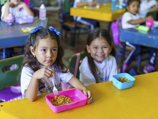 <i>Beneficiarios del programa de merienda escolar de Fundación Ficohsa recibiendo sus alimentos diarios.</i>