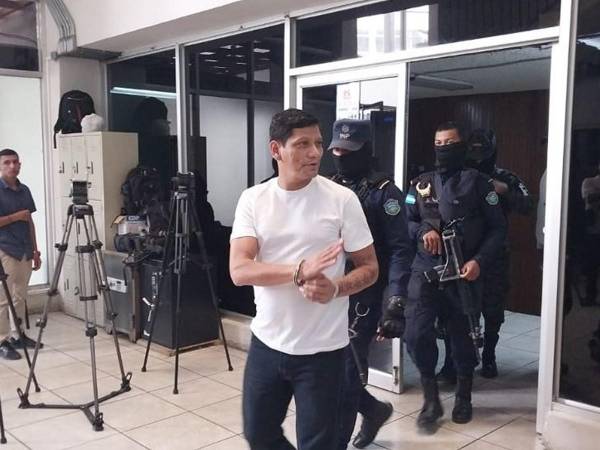 El exfutbolista hondureño fue escoltado por agentes de la Policía Militar y vestía una camiseta de color blanca, quien lanzó un saludo a los medios antes de ingresar a los tribunales.