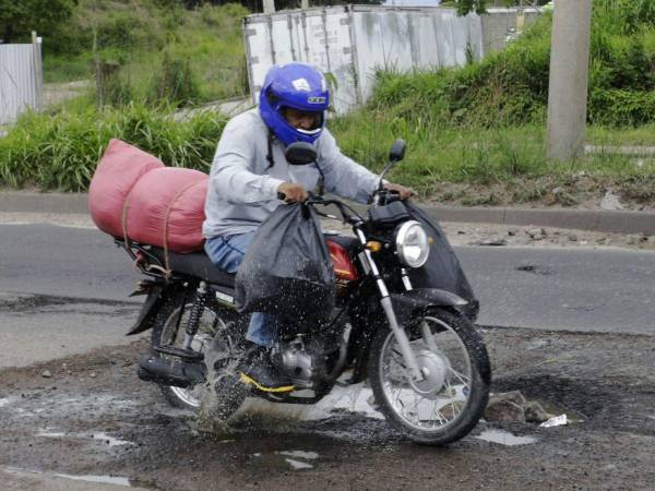 Este conductor de motocicleta estuvo a punto de caer al pasar por un gigantesco bache en el anillo periférico.