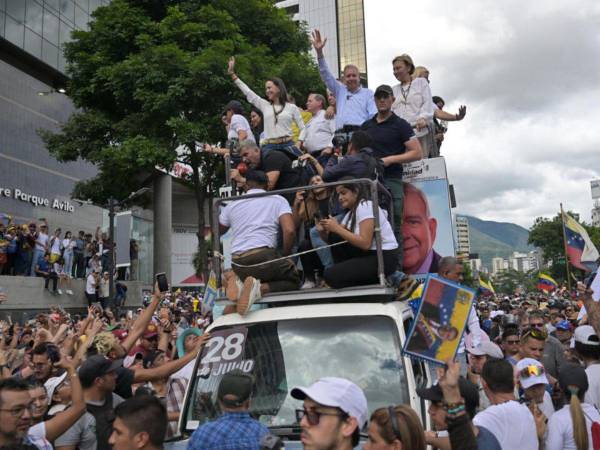 La líder opositora venezolana María Corina Machado y el candidato presidencial Edmundo González Urrutia saludan a sus partidarios durante una manifestación.