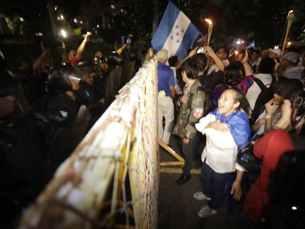 Un fuerte contingente policial de antimotines detrás de vallas metálicas impide esta noche el paso a los hondureños que se han sumado a la marcha de las antorchas que busca llegara a Casa Presidencial para exigir a la mandataria que rectifique su decisión de denunciar al tratado de extradición o su renuncia.