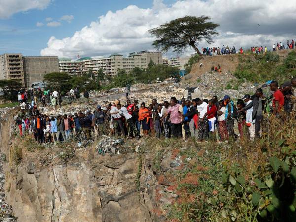 Personas conmocionadas miran el vertedero de basura donde fueron hallados los cuerpos.