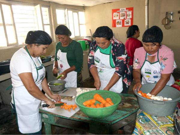 Las madres del Centro de Educación Básica La Buena Nueva trabajan en grupos para preparar los alimentos de los niños.