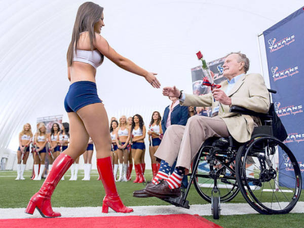 In this photo taken Wednesday, April 17, 2013, former President George H.W. Bush presents a rose to a new Houston Texans cheerleader during a ceremony introducing the new squad at the team's NFL football training facility in Houston. (AP Photo/Houston Chronicle, Smiley N. Pool) MANDATORY CREDIT