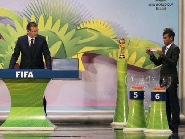 Brazil's Neymar (R) holds up a country name as FIFA's General Secretary Jerome Valcke directs him during the preliminary draw for the 2014 World Cup in Rio de Janeiro, July 30, 2011. Brazil will host the 20th World Cup soccer tournament from June 12 to July 13 in 2014. REUTERS/Sergio Moraes (BRAZIL - Tags: SPORT SOCCER WORLD CUP)